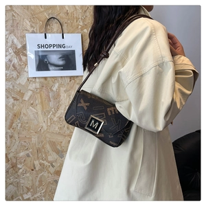Close-up of contrast monogram shoulder bag with gold M-shaped twist lock buckle