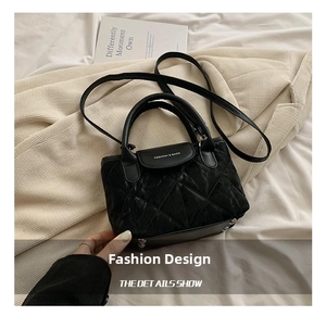 Detail of black quilted bucket bag with adjustable strap and metallic closure