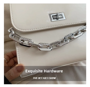 Detail of white leather shoulder bag featuring engraved silver chain and turn-lock closure