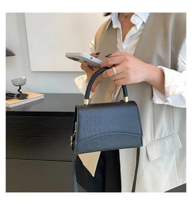 Detailed view of crocodile pattern handbag with braided handle and gold hardware detail