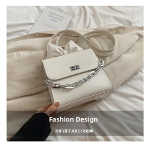Detail view of stylish cream shoulder bag featuring silver chain and decorative bow