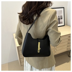 Détail d'un sac hobo en cuir noir avec fermoir doré porté par un mannequin