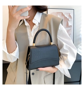 Detail of crocodile pattern handbag with woven handle and gold metal hardware