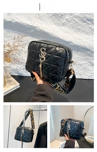 Détail d'un sac bandoulière matelassé noir avec pompon doré et sangle à motifs