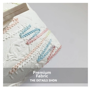 Macro shot of white jacquard fabric with colorful woven geometric texture and embroidery