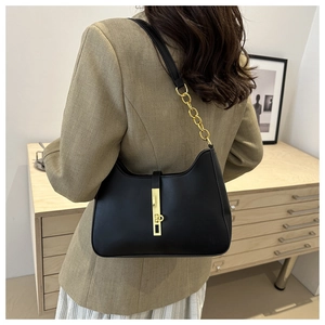 Detail of black matte leather shoulder bag with gold piston lock and chain strap