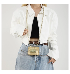 Detail of a mini gold chain bag styled on a white jacket for a chic fashion look