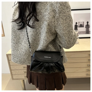 Détail du sac plissé noir en cuir avec chaîne argentée et lettrage FASHION élégant