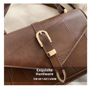 Close-up of golden U-shaped metal buckle on a brown leather crossbody handbag