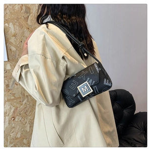 Detail of black crossbody bag featuring abstract prints and a signature M metal clasp