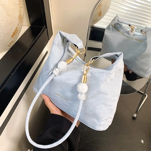 Light blue slouchy tote bag with woven shoulder strap and marble bead decoration