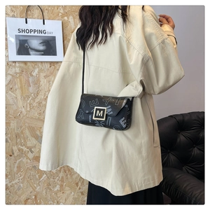 Detail of contrast lettering pattern and golden M-buckle on a chic shoulder bag