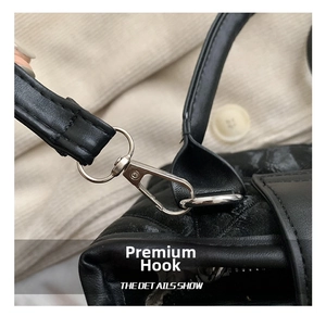 Macro detail of the black quilted leather texture and silver metal hook on the bucket bag