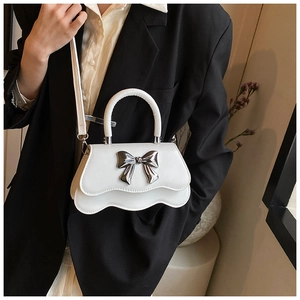 Détail du mini sac blanc avec nœud en métal argenté et bordure ondulée chic