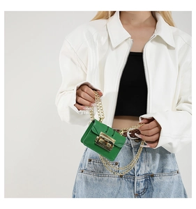Detailed close-up of a green mini square bag with gold chain and metal buckle