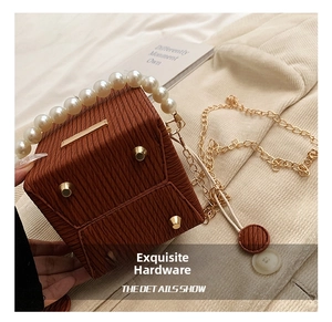 Detail of caramel textured bucket bag showing pearl handle and gold protective feet