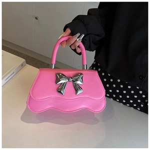 Détail du sac carré rose Barbie avec nœud en métal argenté et bord ondulé