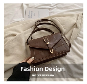 Detail of vintage brown shoulder bag with geometric stitching and golden U-shaped buckle