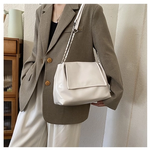 Close-up of white glossy tote bag with silver chain strap and leather stitching details