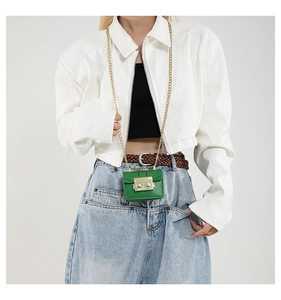 Detail of a green mini chain crossbody bag with golden metal lock and textured finish