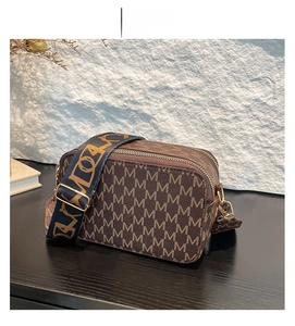 Detail of coffee brown crossbody camera bag with jacquard strap and gold zippers