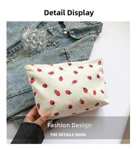 Detail of soft corduroy clutch bag with strawberry print and red accents