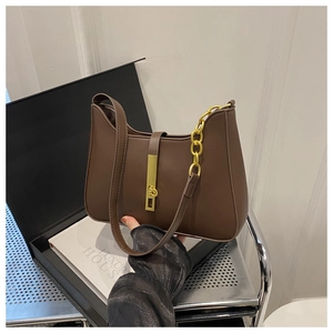 Détail d'un sac sous le bras en cuir marron avec chaîne dorée et boucle vintage
