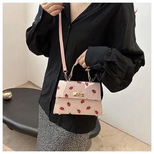 Close-up of pink corduroy crossbody bag with strawberry embroidery and gold lock