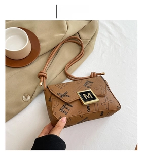 Detail of a brown leather crossbody bag featuring letter patterns and a golden M metal buckle
