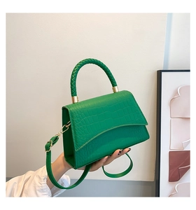 Detail of green crocodile pattern handbag with woven handle and gold hardware