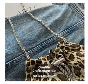 Detail shot of leopard print fabric bucket bag with a fine metal chain shoulder strap