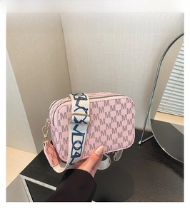 Detailed view of pink camera bag with Monogram M pattern and wide woven strap