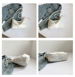 Detail view of white embroidered tote bag with textured monogram and drawstring handles