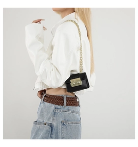 Detail of a black leather square bag with gold chain strap on a stylish white jacket outfit