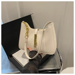Détail du sac demi-lune en cuir crème avec boucles dorées et chaîne décorative chic