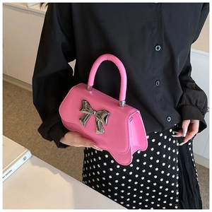 Sac à main rose avec un nœud argenté métallique et un contour de fond irrégulier