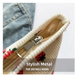 Detail of silver metal zipper on white corduroy bag featuring a red strawberry pattern
