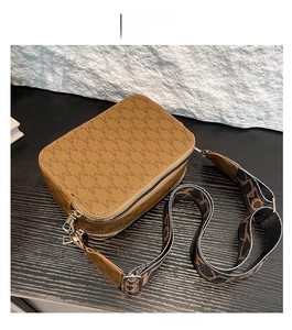 Detail of brown crossbody bag with M-pattern texture and wide jacquard woven strap
