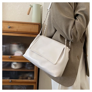 Close-up of a white leather chain shoulder bag shown on model in a casual lifestyle setting