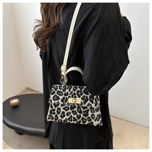 Detail of leopard print canvas handbag featuring gold metal turn-lock and white strap