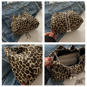 Detail view of leopard print bucket bag with silver chain and pearl drawstring charms