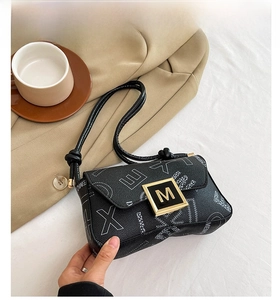 Close-up of black leather shoulder bag with white letter print and gold M buckle