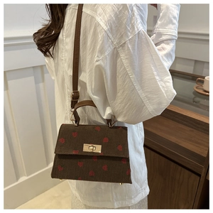 Detail showing brown corduroy texture and red strawberry embroidery on stylish small bag