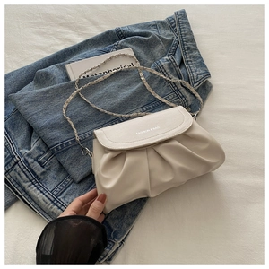 Détail du sac bandoulière beige plissé avec bandoulière en chaîne et logo imprimé