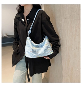 Detail of light blue tote bag featuring pleated fabric, rainbow embroidery and bow accents