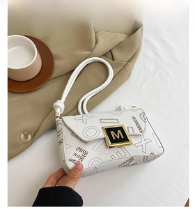 Detail view of beige crossbody bag with geometric patterns and golden M logo clasp
