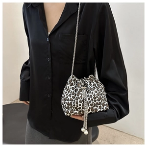 Detailed macro of leopard print bucket bag featuring pearl charms and silver chain strap