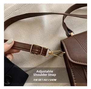 Detail of adjustable shoulder strap on dark brown leather bag with gold hardware