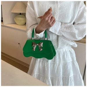 Détail du sac à main vert avec nœud argenté et bord inférieur ondulé élégant