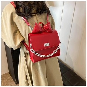 Detail of red patent leather backpack with large bow and silver chunky chain decoration